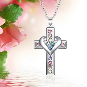 Silver cross necklace with colorful rhinestones and heart pendant on a water ripple surface