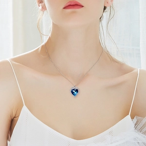 Close-up of heart-shaped blue crystal necklace with diamond halo on neck