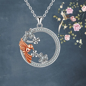 Detailed view of hummingbird and flower pendant with diamonds on a textured dark background
