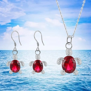 Detailed shot of silver turtle jewelry set featuring vibrant oval red crystal inlay