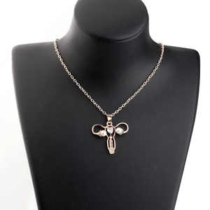 Détail macro du pendentif utérus plaqué or avec zircon coeur et perles sur support