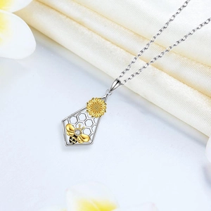 Collar bicolor con colgante de abeja y girasol sobre fondo de satén crema elegante