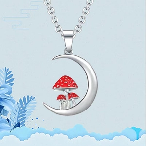 Close-up of silver moon pendant with red mushrooms and delicate silver chain necklace