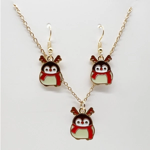 Detailed view of golden penguin earrings and necklace set with festive Christmas theme
