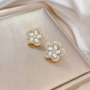 Gros plan de boucles d'oreilles fleur de cerisier avec finition dorée et zircons