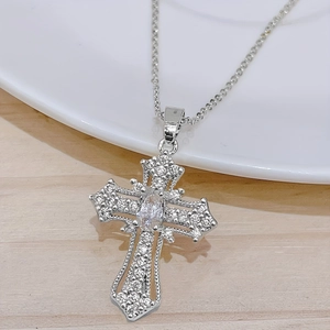 Elegante silberne Kreuzkette mit funkelnden Kristallen auf hellem Holzgrundstück