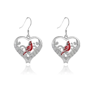 Macro detail of silver heart-shaped bird earrings with vibrant red cardinal inlay