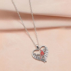 Detail of silver heart pendant featuring a red cardinal bird with crystal accents on silk