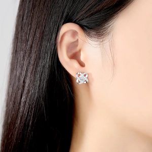 Silver four-petal flower stud earrings with pavé crystals on a female model
