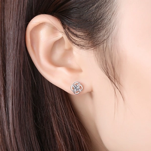 Minimalist silver four-leaf clover stud earring with sparkling central zircon on ear