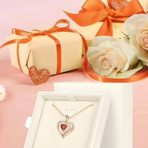 Close-up of rose gold heart pendant with red birthstone in a white jewelry gift box