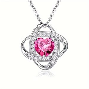 Detail of silver heart pendant with pink gemstone and white diamonds on white background