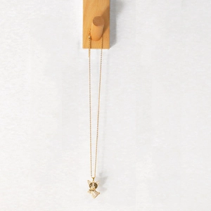 Cute golden French Bulldog necklace with shimmering rhinestones on a wooden hook