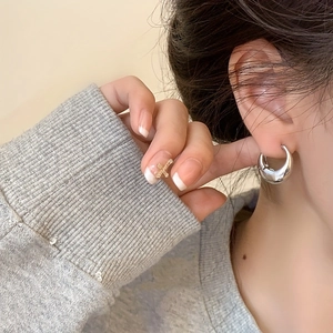 Close-up of polished silver teardrop earrings worn for a modern minimalist look