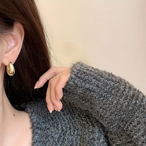 Close-up of elegant gold water drop earrings worn by a model for a minimalist look