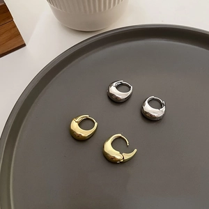 Detail of minimalist geometric metal hoop earrings in polished gold and silver finishes