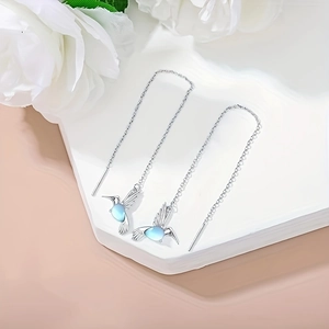 Orecchini a filo con colibrì in argento e pietre blu su supporto bianco