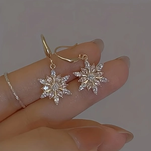 Elegante goldene Schneeflocken-Ohrhänger mit funkelnden Kristallen in der Hand
