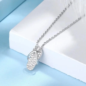 Glinsterende teenslipper hanger ketting met kristallen op blauwe achtergrond met veer