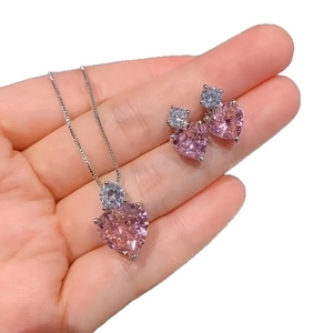 Schmuckset mit rosa Herz-Halskette und Ohrringen in der Hand für die Größenansicht