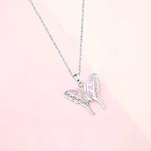 Detalle de un colgante de mariposa plateado con incrustación de opalo rosa y cadena fina