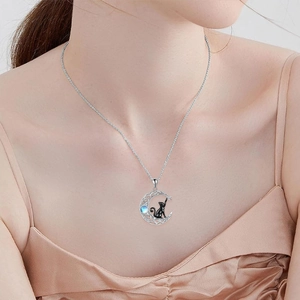 Elegant silver crescent moon necklace with a black cat and blue gemstone on a model