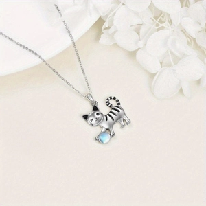 Detalle del colgante de gato plateado con perla azul en una cadena delicada
