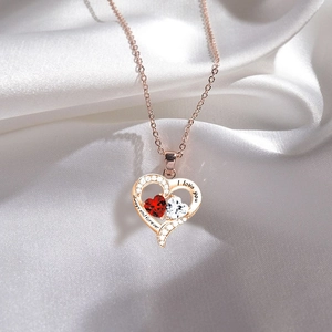 Collar de corazón oro rosa con gemas dobles y grabado sobre fondo de seda blanca fina