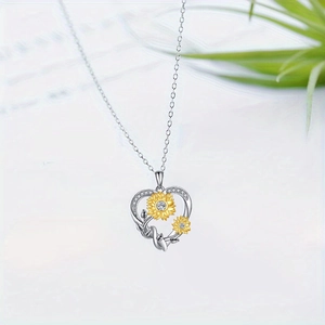 Macro shot of silver heart pendant with golden sunflowers and inlaid crystals detail