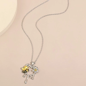 Dettaglio di una collana a cuore in argento con ciondoli ape e fiore su catena a maglie