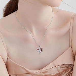 Elegant angel wing heart pendant necklace with red gemstone and micro diamonds on model