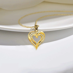 Goldene Herz-Halskette mit Zirkoniasteinen auf weißer Keramik für einen eleganten Look