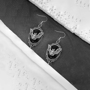 Detail of gothic silver-tone bat earrings with black stone inlay for Halloween outfits