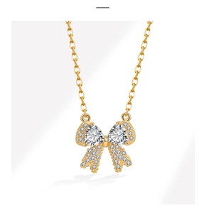 Detailopname van een gouden strikhanger met fonkelende zirkonia en een fijne gouden ketting