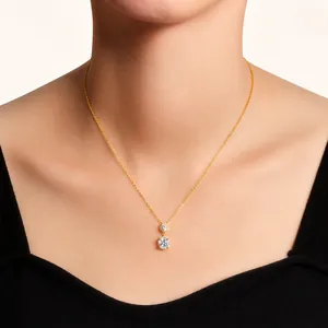 Detail shot of a double-diamond pendant necklace on a gold chain worn by a model