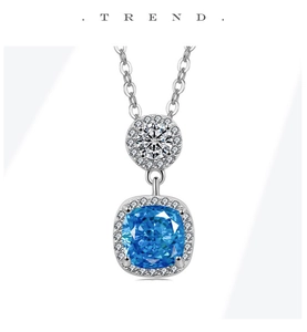 Macro shot of silver necklace with blue cushion-cut gemstone and micro-pave pendant