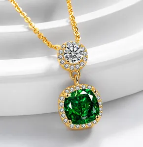 Close-up of double pendant necklace with green emerald cut stone and gold chain