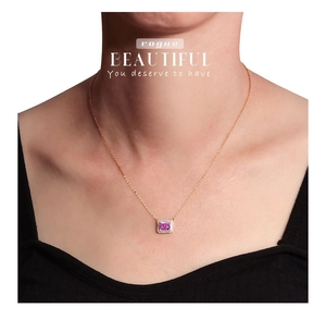 Macro detail of a rose gold necklace featuring a square pink gemstone pendant on a model