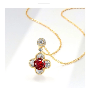 Macro di collana dorata con ciondolo a quadrifoglio, gemma rossa e diamanti a baguette