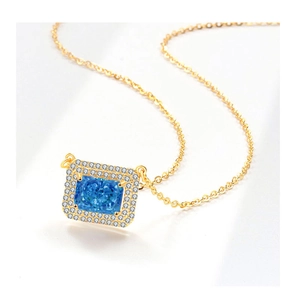 Detail showing square blue gemstone pendant with double halo setting on gold chain necklace