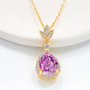 Macro shot of a pear-cut pink gemstone pendant with halo diamonds on a thin gold chain