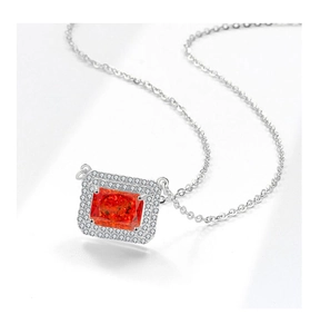 Macro shot of silver necklace with emerald cut orange gemstone and zircon halo