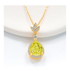 Dettaglio macro di una collana con gemma gialla a goccia e dettagli in diamanti bianchi