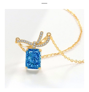 Close-up of a blue rectangle gemstone pendant with a sparkling diamond bow and gold chain