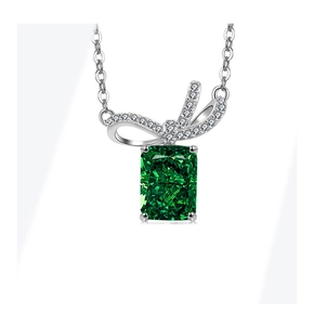 Macro detail of emerald-cut green gemstone pendant with a diamond bow in S925 silver
