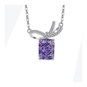 Macro detail of Radiant cut purple gemstone pendant with pavé diamond bow on silver chain