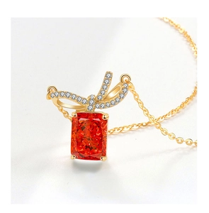 Macro detail of rectangle orange zircon pendant with bowknot design and gold finish