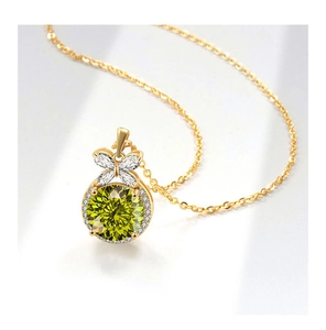 Close-up of a luxury bow pendant with round yellow-green gemstone and gold chain necklace