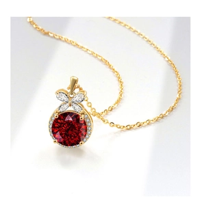 Macro detail of red round cut gemstone necklace with gold bow and pavé diamond halo