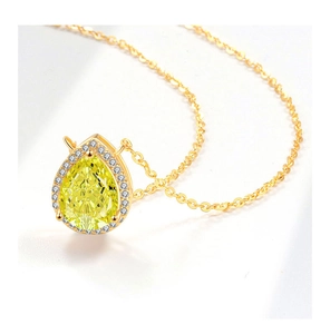 Macro shot of yellow pear cut stone necklace with diamond halo and gold chain